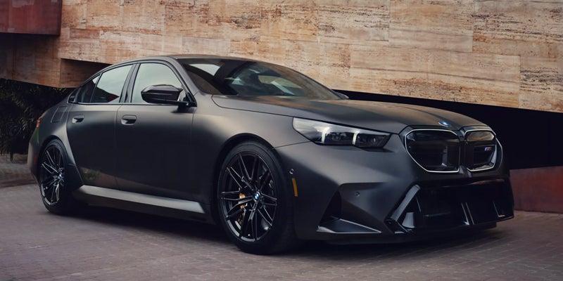 A dark matte-finish sedan is positioned at a slight angle, facing toward the right side of the image