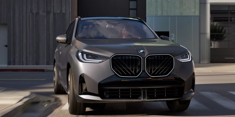 Gray BMW SUV driving through an urban area.