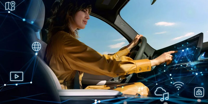 Driver using a vehicle touchscreen with connected car technology icons displayed